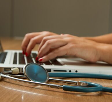 person sitting while using laptop computer and green stethoscope near